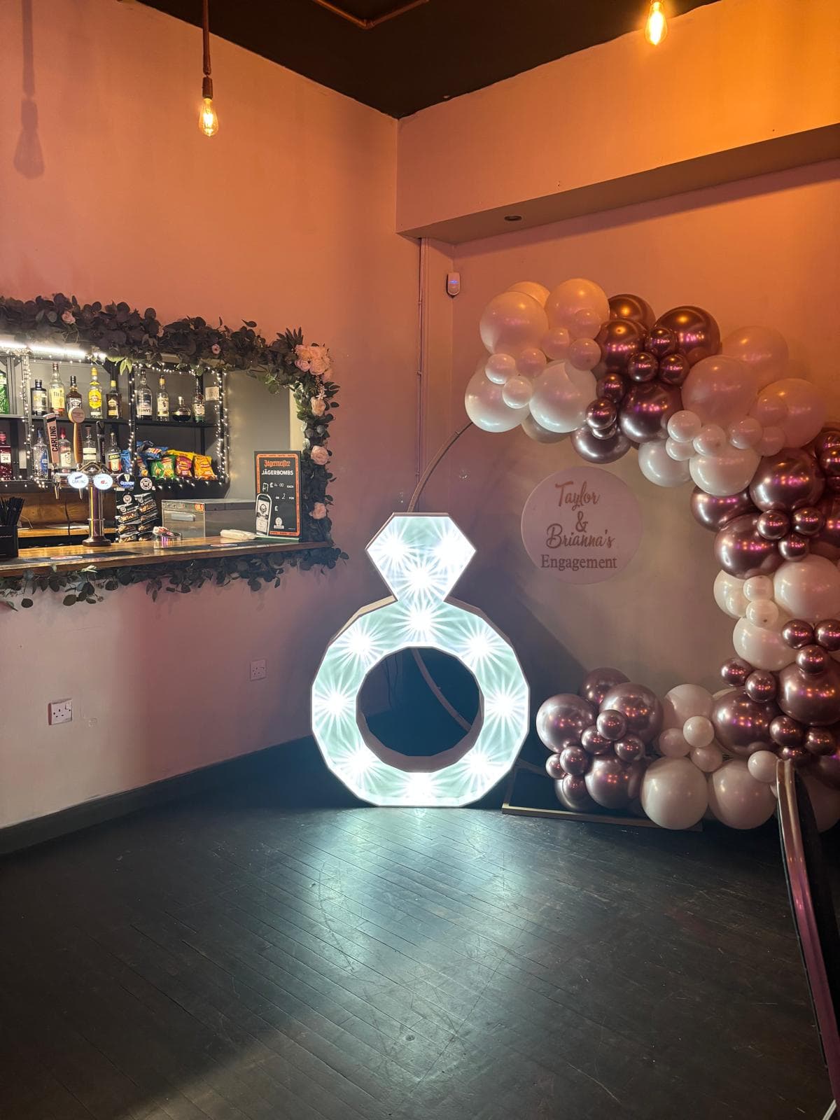 Giant light-up engagement ring beside a rose gold balloon arch at Gracy's