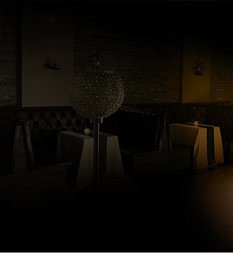 Draped tables and booth seating in low warm light at Gracy's function room