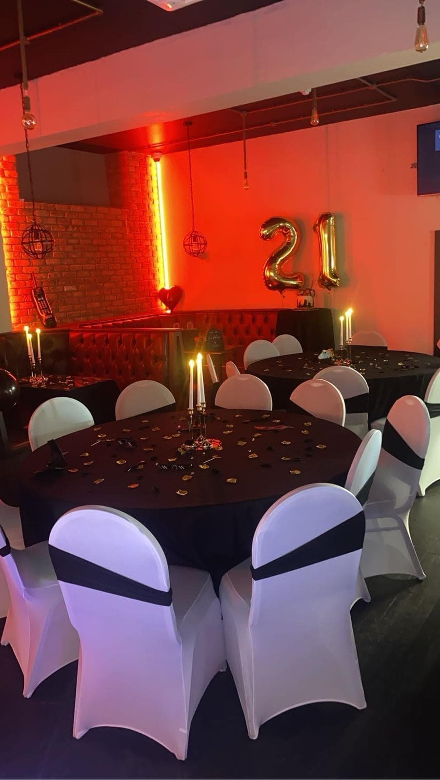 Round tables with candlelight under a warm red glow at Gracy's